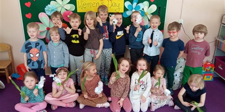 Powiększ grafikę: Grupa pozuje do zdjęcia. Dziewczynki trzymają tulipany